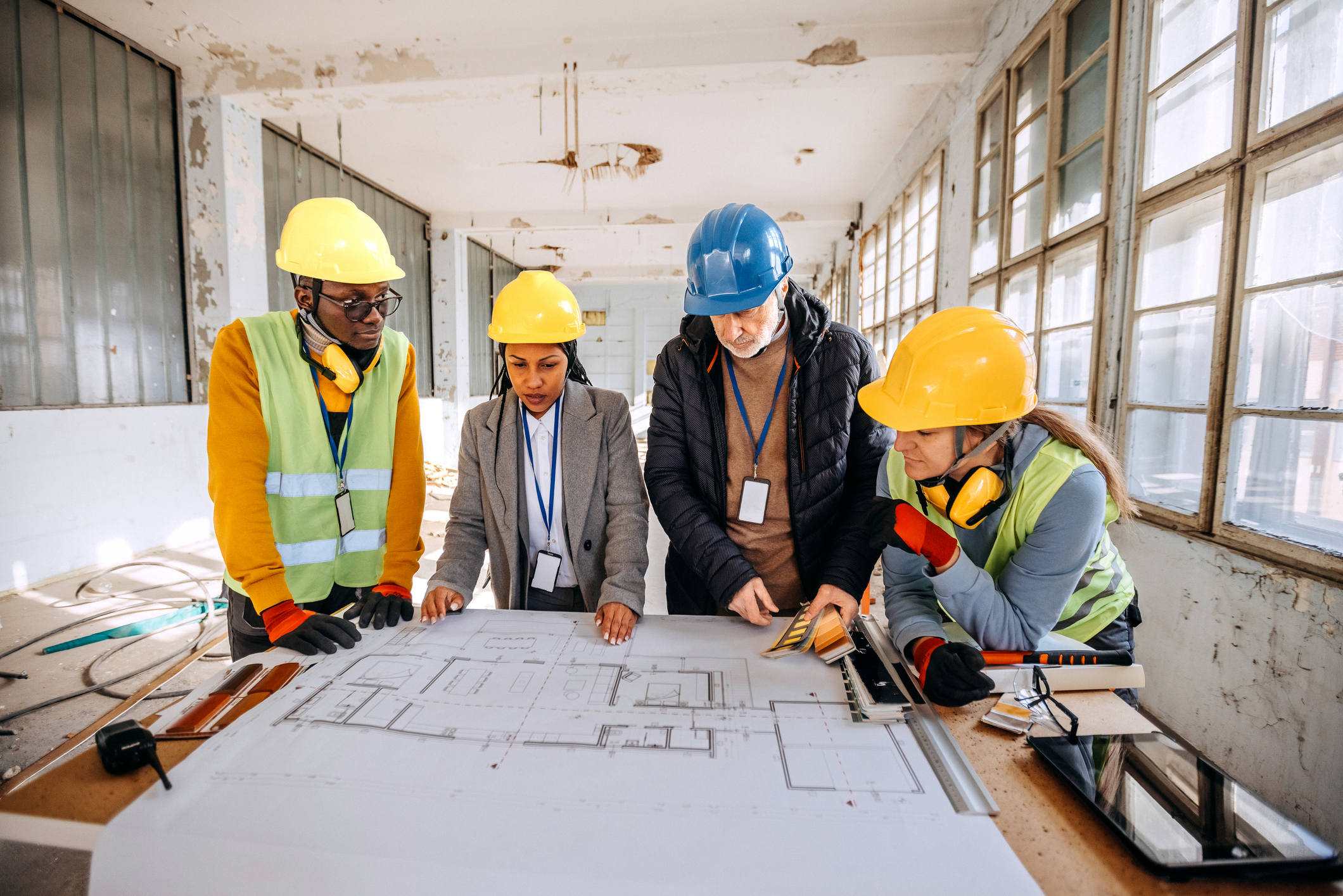 Architects looking at the architectural project and explaining to construction worker what to do